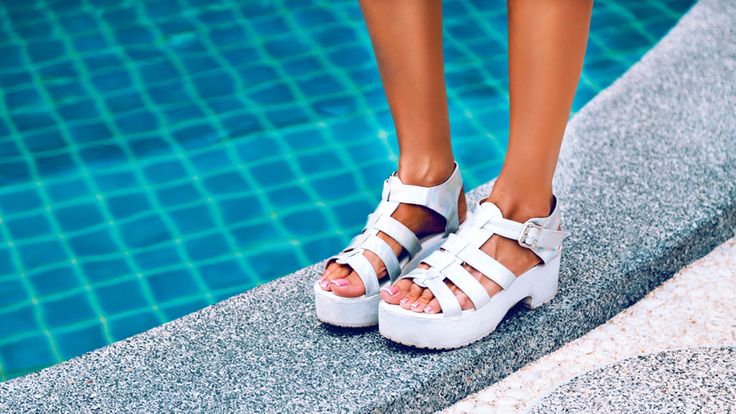 Crop photos. Female feet in white sandals with heels. It stands on the edge of the pool with blue water. Stylish image of trendy silver summer sandals.; Shutterstock ID 284902886; PO: TODAY.COM